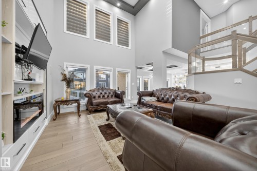 Living area with light wood-style floors and a high ceiling - 4406 Triomphe Close, Beaumont, AB - Indoor With Fireplace