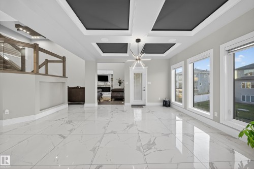 Unfurnished living room with coffered ceiling, a chandelier, and light marble finish floors - 4406 Triomphe Close, Beaumont, AB - Indoor Photo Showing Other Room