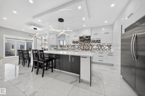 Kitchen featuring modern cabinets, open shelves, white cabinetry, and stainless steel refrigerator - 4406 Triomphe Close, Beaumont, AB - Indoor