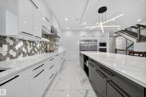 Two tone kitchen featuring modern cabinets, light stone countertops, and two tone cabinets - 4406 Triomphe Close, Beaumont, AB - Indoor Photo Showing Kitchen With Upgraded Kitchen