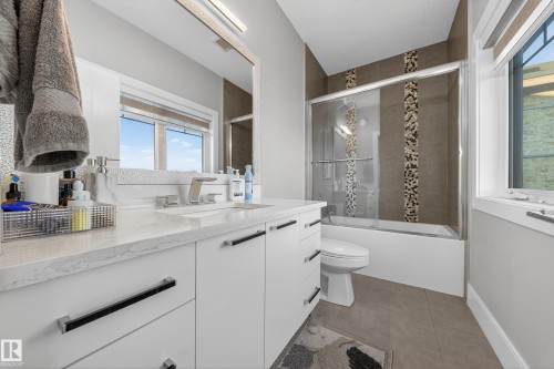 Bathroom featuring shower / bath combination with glass door, vanity, and light tile patterned floors - 4406 Triomphe Close, Beaumont, AB - Indoor Photo Showing Bathroom