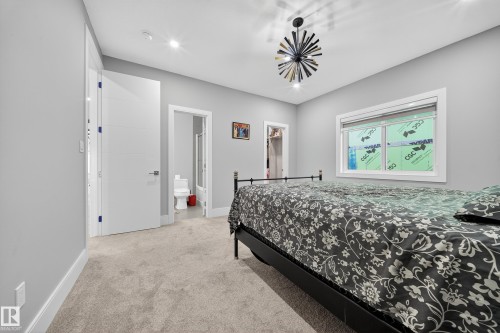Bedroom featuring a spacious closet, light colored carpet, recessed lighting, and ensuite bathroom - 4406 Triomphe Close, Beaumont, AB - Indoor Photo Showing Bedroom