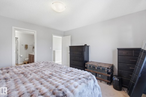 Carpeted bedroom with a textured ceiling and ensuite bath - 3087 Arthurs Crescent, Edmonton, AB - Indoor Photo Showing Bedroom