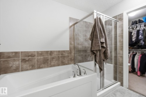 Full bathroom featuring a textured ceiling, a shower stall, a bath, and a walk in closet - 3087 Arthurs Crescent, Edmonton, AB - Indoor Photo Showing Bathroom