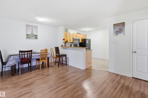 Kitchen with a peninsula, light wood finish cabinets, light wood-style flooring, freestanding refrigerator, and stainless steel microwave - 407 2305 35A Avenue, Edmonton, AB - Indoor