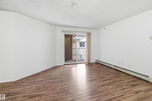 Spare room featuring a baseboard heating unit, wood finished floors, and a textured ceiling - 407 2305 35A Avenue, Edmonton, AB - Indoor Photo Showing Other Room