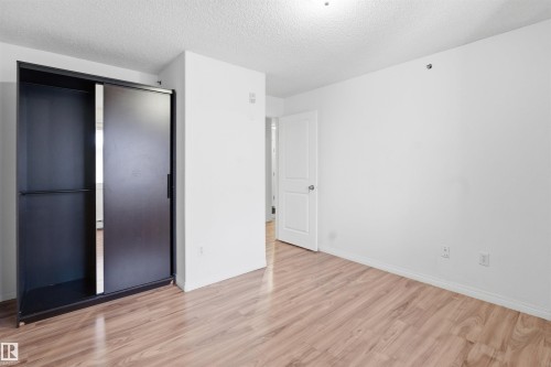 Unfurnished bedroom with a textured ceiling, wood finished floors, and a closet - 407 2305 35A Avenue, Edmonton, AB - Indoor Photo Showing Other Room