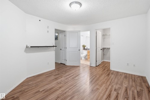 Unfurnished bedroom featuring light wood-style floors, a walk in closet, a textured ceiling, and connected bathroom - 407 2305 35A Avenue, Edmonton, AB - Indoor Photo Showing Other Room