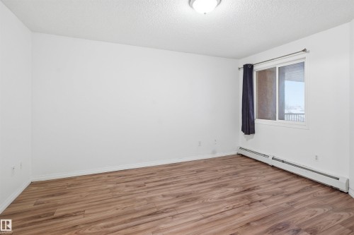 Empty room with a baseboard radiator, light wood-type flooring, and a textured ceiling - 407 2305 35A Avenue, Edmonton, AB - Indoor Photo Showing Other Room