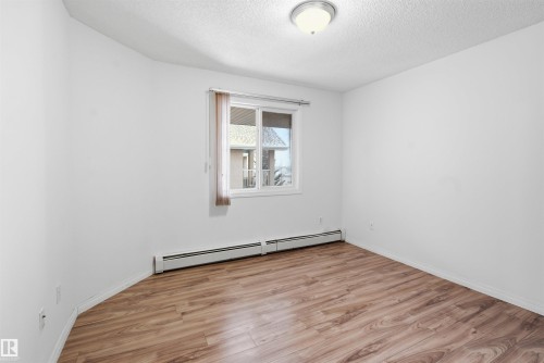 Spare room featuring light wood-type flooring, a baseboard radiator, and a textured ceiling - 407 2305 35A Avenue, Edmonton, AB - Indoor Photo Showing Other Room