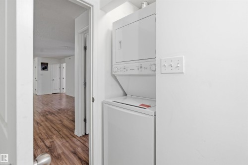 Laundry area with dark wood-type flooring and stacked washer / drying machine - 407 2305 35A Avenue, Edmonton, AB - Indoor Photo Showing Laundry Room