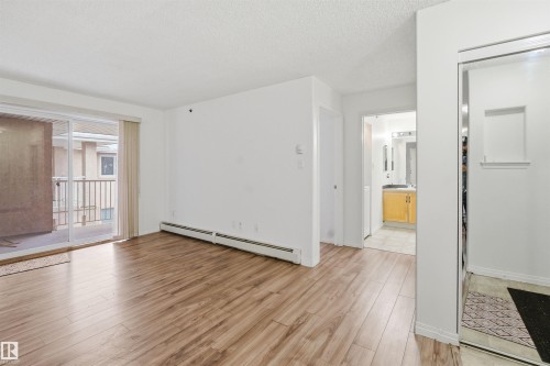 Empty room featuring a baseboard heating unit, light wood finished floors, and a textured ceiling - 407 2305 35A Avenue, Edmonton, AB - Indoor Photo Showing Other Room