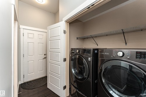 Laundry area with dark wood-style floors and washing machine and dryer - 6963 19A Avenue, Edmonton, AB - Indoor Photo Showing Laundry Room
