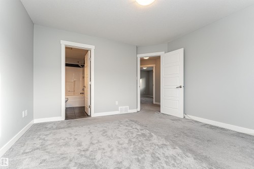 Unfurnished bedroom featuring light colored carpet and connected bathroom - 6963 19A Avenue, Edmonton, AB - Indoor