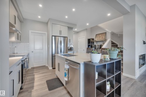 Kitchen with stainless steel appliances, light wood-style floors, an island with sink, recessed lighting, and backsplash - 157 Larch Crescent, Leduc, AB - Indoor Photo Showing Kitchen With Double Sink With Upgraded Kitchen
