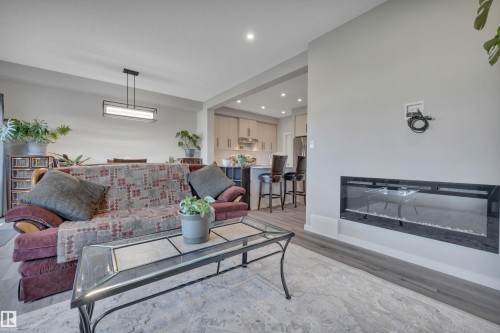 Living area with a glass covered fireplace, recessed lighting, and light wood-type flooring - 157 Larch Crescent, Leduc, AB - Indoor Photo Showing Living Room With Fireplace