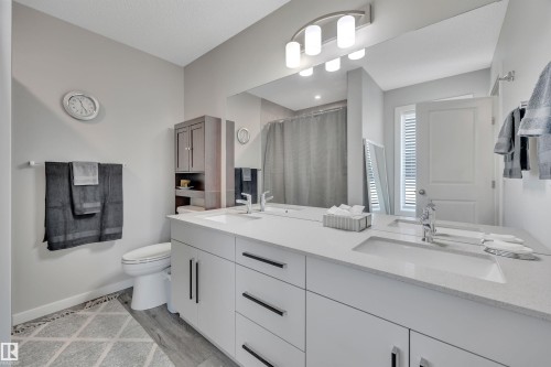 Bathroom with curtained shower, double vanity, and light wood-style flooring - 157 Larch Crescent, Leduc, AB - Indoor Photo Showing Bathroom