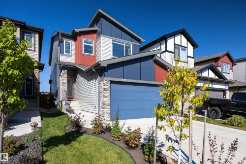 View of front of property featuring stone siding, concrete driveway, a front yard, and an attached garage - 157 Larch Crescent, Leduc, AB - Outdoor