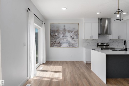 Kitchen featuring white cabinets, modern cabinets, decorative light fixtures, light stone counters, and stainless steel electric range oven - 5747 Kootook Way, Edmonton, AB - Indoor Photo Showing Kitchen With Upgraded Kitchen