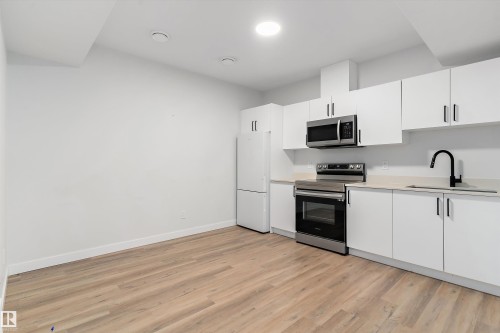 Kitchen with stainless steel appliances, white cabinetry, and light wood-style floors - 5747 Kootook Way, Edmonton, AB - Indoor Photo Showing Kitchen