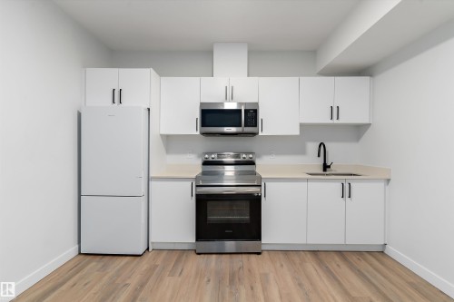 Kitchen with stainless steel appliances, white cabinets, light wood finished floors, and light stone countertops - 5747 Kootook Way, Edmonton, AB - Indoor Photo Showing Kitchen