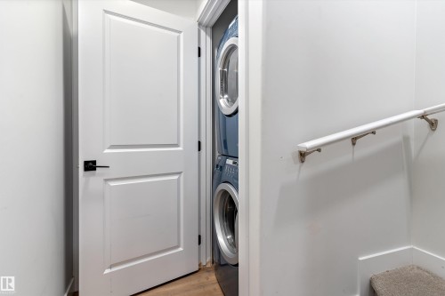 Laundry area with stacked washer and clothes dryer and light wood-type flooring - 5747 Kootook Way, Edmonton, AB - Indoor Photo Showing Laundry Room