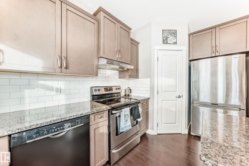 Kitchen with stainless steel appliances, light stone counters, dark wood-style flooring, and backsplash - 1908 69 Street, Edmonton, AB - Indoor Photo Showing Kitchen With Upgraded Kitchen