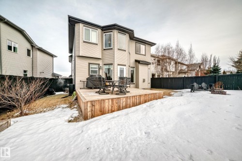 Snow covered back of property featuring a fire pit, a fenced backyard, a deck, and outdoor dining area - 1908 69 Street, Edmonton, AB - Outdoor