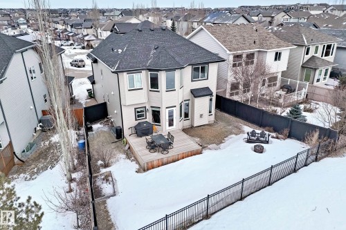 Snow covered rear of property featuring a fire pit, a wooden deck, a fenced backyard, and a residential view - 1908 69 Street, Edmonton, AB - Outdoor
