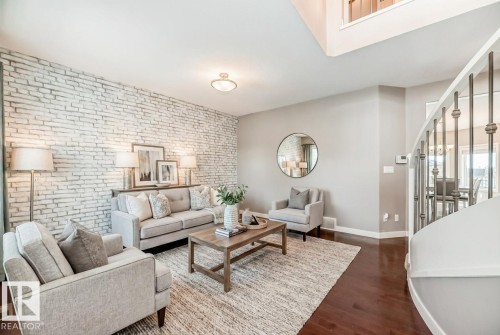 Living area with brick wall, dark wood-type flooring, and an accent wall - 1908 69 Street, Edmonton, AB - Indoor Photo Showing Living Room