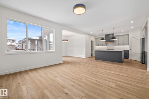 Kitchen featuring an island with sink, open floor plan, light countertops, decorative light fixtures, and gray cabinetry - 4543 Knight Wynd, Edmonton, AB - Indoor