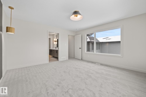 Unfurnished bedroom featuring light colored carpet and connected bathroom - 4543 Knight Wynd, Edmonton, AB - Indoor Photo Showing Other Room
