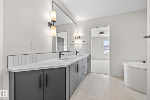 Full bathroom with double vanity, a soaking tub, light carpet, and light tile patterned flooring - 4543 Knight Wynd, Edmonton, AB - Indoor Photo Showing Bathroom