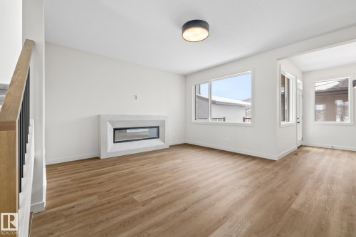Unfurnished living room with light wood finished floors and a glass covered fireplace - 4543 Knight Wynd, Edmonton, AB - Indoor Photo Showing Other Room With Fireplace