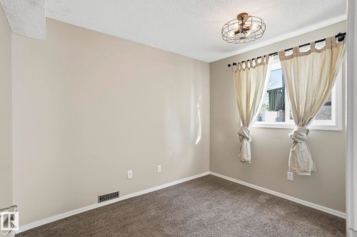 Empty room with a textured ceiling and dark carpet - Edmonton, AB - Indoor Photo Showing Other Room