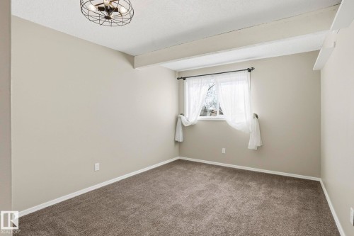 Carpeted empty room featuring a textured ceiling and beam ceiling - Edmonton, AB - Indoor Photo Showing Other Room