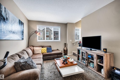 Living room with wood finished floors and a textured ceiling - 8 320 Secord Boulevard, Edmonton, AB - Indoor Photo Showing Living Room
