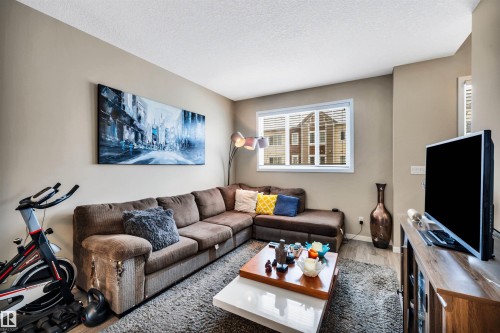 Living room featuring wood finished floors and a textured ceiling - 8 320 Secord Boulevard, Edmonton, AB - Indoor Photo Showing Living Room