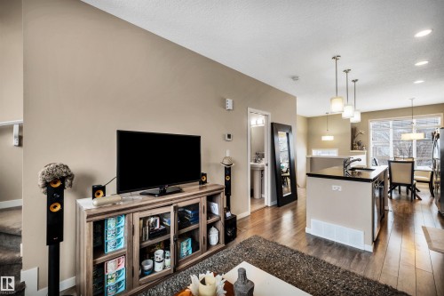 Living room featuring dark wood-style floors, recessed lighting, and a textured ceiling - 8 320 Secord Boulevard, Edmonton, AB - Indoor