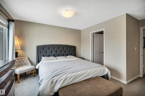 Carpeted bedroom featuring baseboards and a textured ceiling - 8 320 Secord Boulevard, Edmonton, AB - Indoor Photo Showing Bedroom