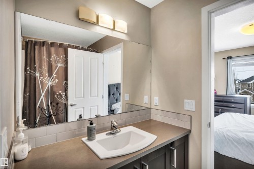 Ensuite bathroom with vanity, decorative backsplash, and curtained shower - 8 320 Secord Boulevard, Edmonton, AB - Indoor Photo Showing Bathroom