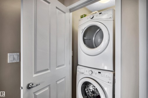 Laundry area featuring stacked washer / dryer - 8 320 Secord Boulevard, Edmonton, AB - Indoor Photo Showing Laundry Room