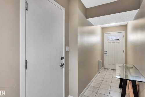 Foyer with baseboards and light tile patterned flooring - 8 320 Secord Boulevard, Edmonton, AB - Indoor Photo Showing Other Room