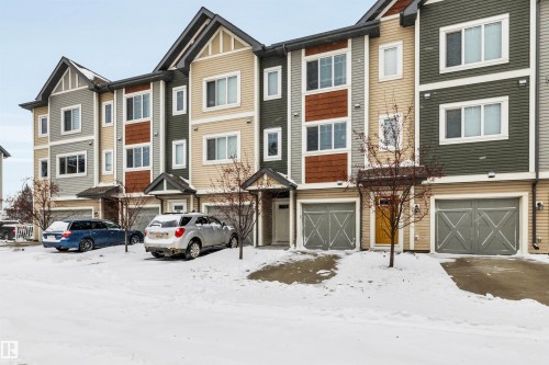 View of front of home with a garage and a residential view - 8 320 Secord Boulevard, Edmonton, AB - Outdoor With Facade