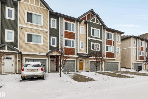 View of front of property with a garage and a residential view - 8 320 Secord Boulevard, Edmonton, AB - Outdoor With Facade
