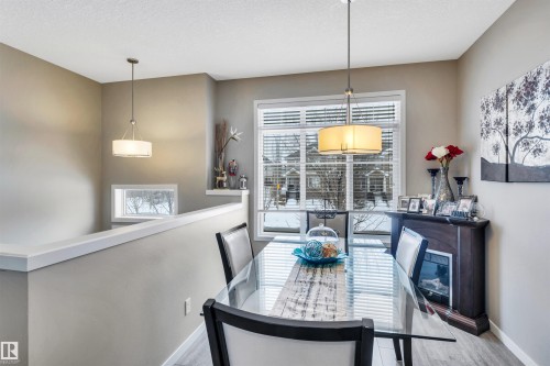 Dining room with wood finished floors and a textured ceiling - 8 320 Secord Boulevard, Edmonton, AB - Indoor Photo Showing Dining Room