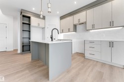 Kitchen with an island with sink, pendant lighting, light wood finished floors, light stone counters, and recessed lighting - 