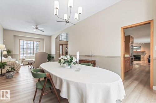 Dining area with a ceiling fan, light wood-type flooring, a stone fireplace, a chandelier, and lofted ceiling - 121 Weaver Drive, Edmonton, AB - Indoor Photo Showing Dining Room