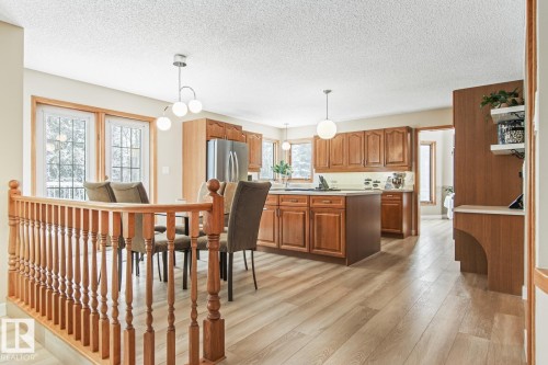 Kitchen featuring wood finish cabinetry, hanging light fixtures, light countertops, freestanding refrigerator, and light wood-style floors - 121 Weaver Drive, Edmonton, AB - Indoor