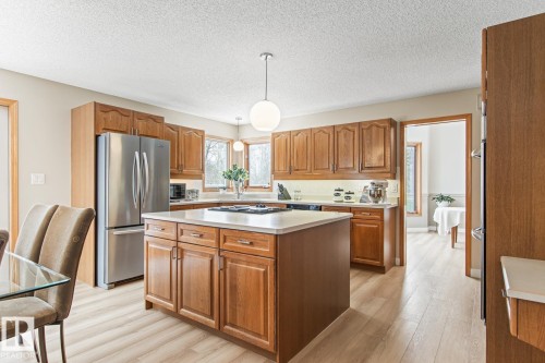 Kitchen featuring wood finish cabinets, pendant lighting, stainless steel appliances, a center island, and light countertops - 121 Weaver Drive, Edmonton, AB - Indoor Photo Showing Kitchen With Double Sink